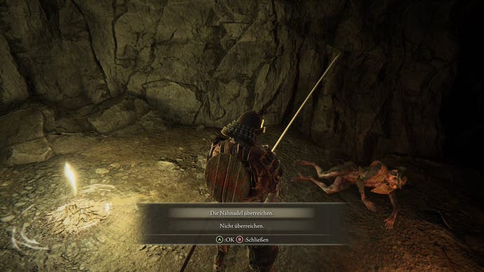 A warrior watches a demihuman lying on the ground in a cave in Elden Ring
