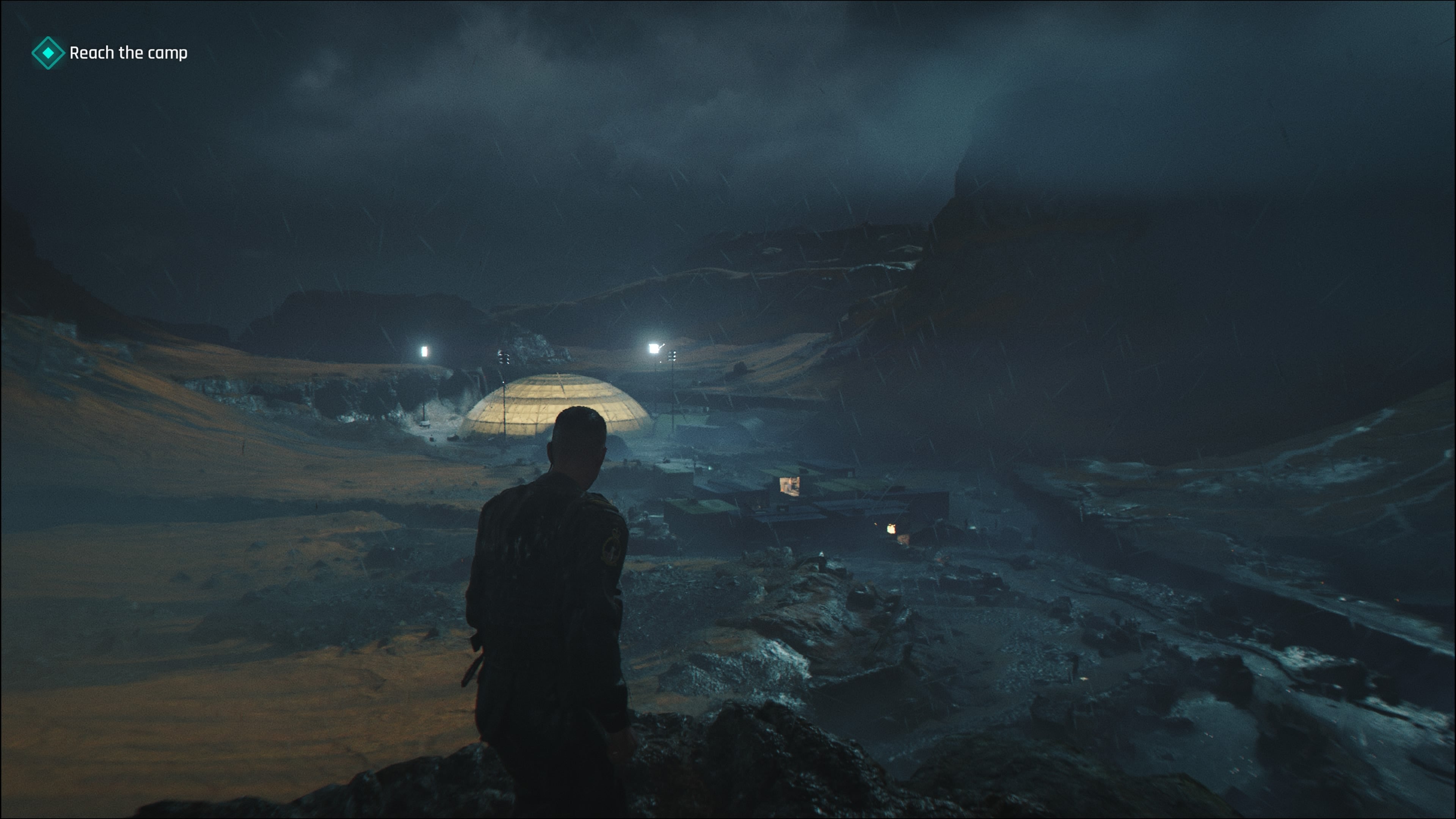 A screenshot of 007 First Light, showing Bond in Iceland overlooking an enemy encampment at night. A large, illuminated dome structure sits at the end of the camp.