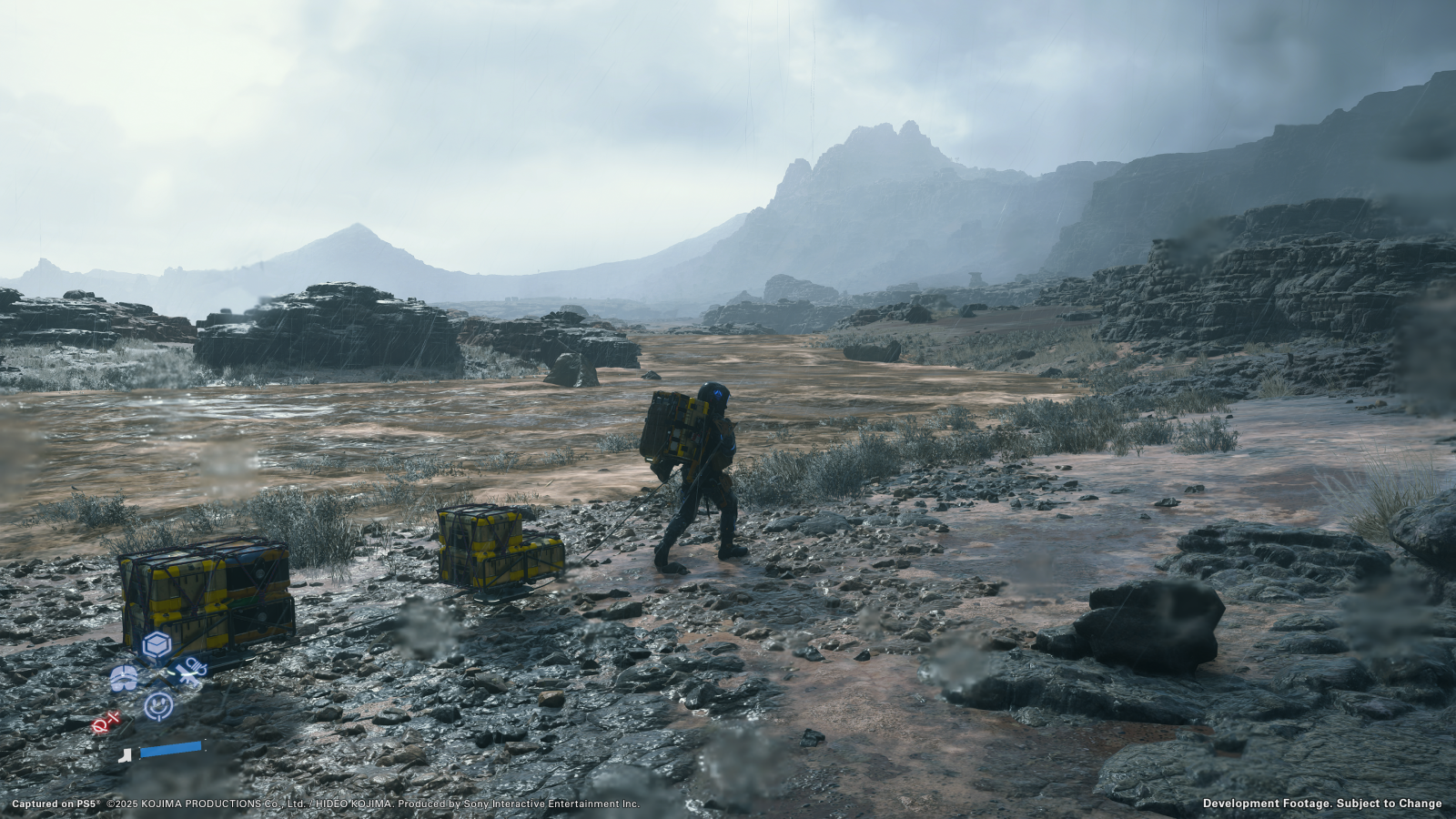 Death Stranding 2 screenshot showing Sam pulling multiple packages through a barren, desolate, grey rocky area