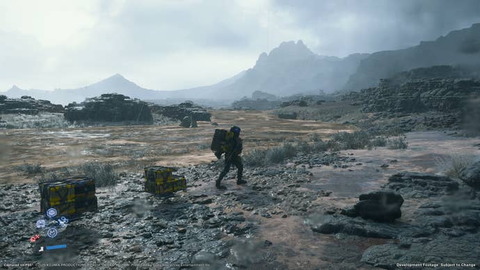 Death Stranding 2 screenshot showing Sam pulling multiple packages through a barren, desolate, grey rocky area