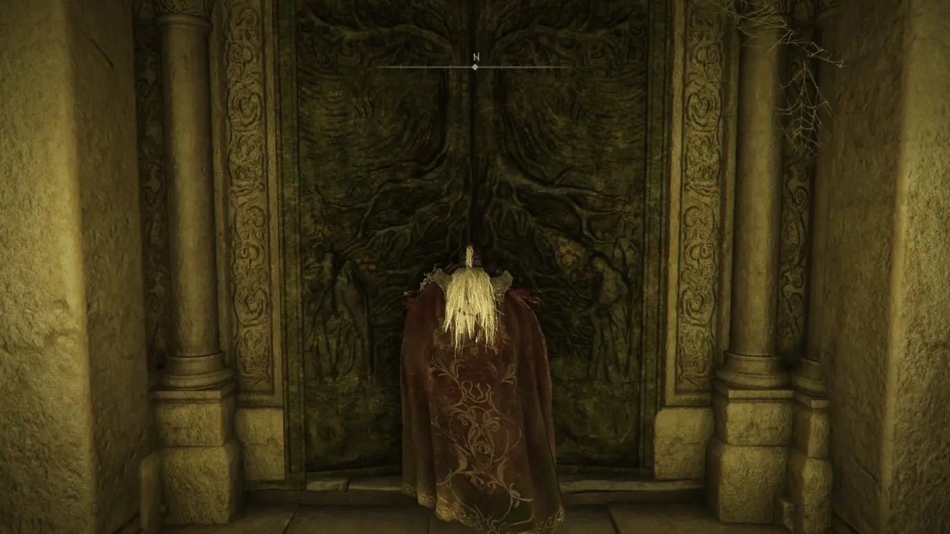 A warrior stands in front of a large door in Auriza Hero&rsquo;s Grave in Elden Ring.