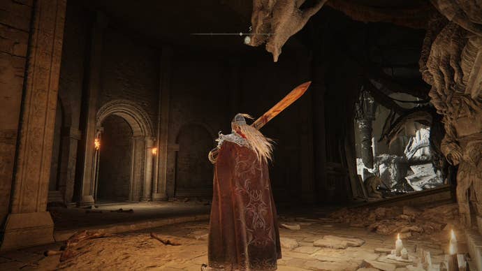 A warrior goes down a passage in Crumbling Farum Azula in Elden Ring.