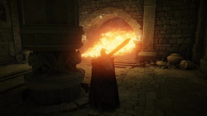 Un guerrier se tient derrière un pilier enflammé dirigé vers un couloir de la tombe du héros Auriza à Elden Ring.