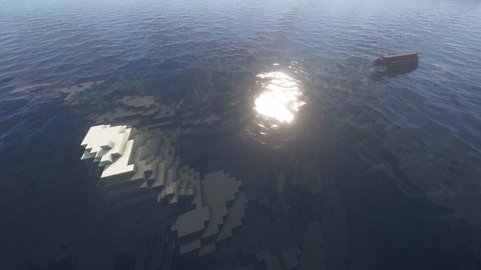 Ein Minecraft-Ozean mit einer winzigen Sandinsel auf der linken Seite und einem Schiffswrack, das auf der rechten Seite aus dem Meer ragt.