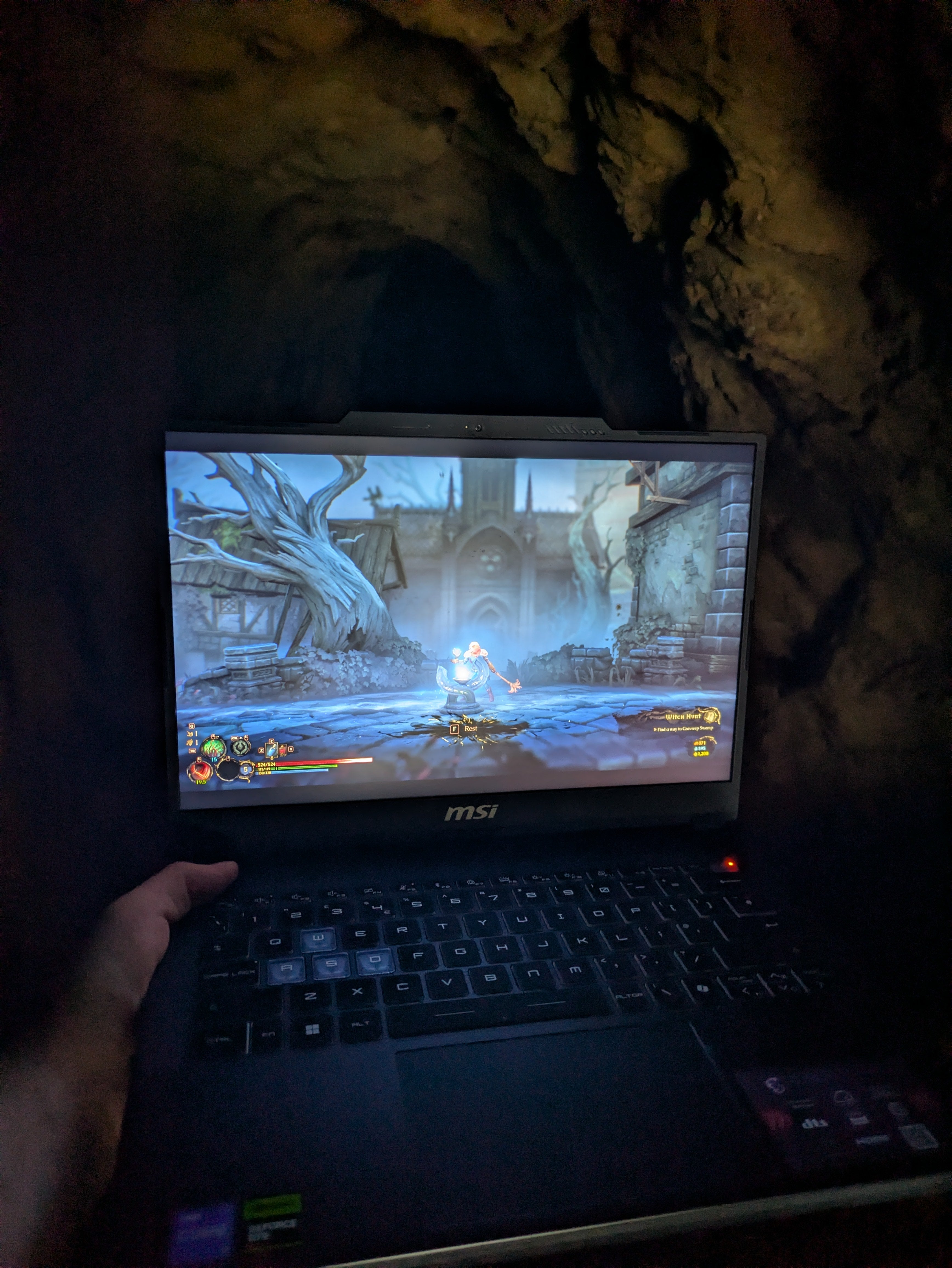 A laptop playing the videogame Mandragora inside a spooky cave.