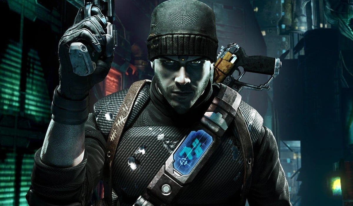 The gruff white gun-toting lead of Human Head's cancelled Prey 2, wearing a black suit with a beanie and some cybernetic gadgets, in a dark alien metropolis. - 1