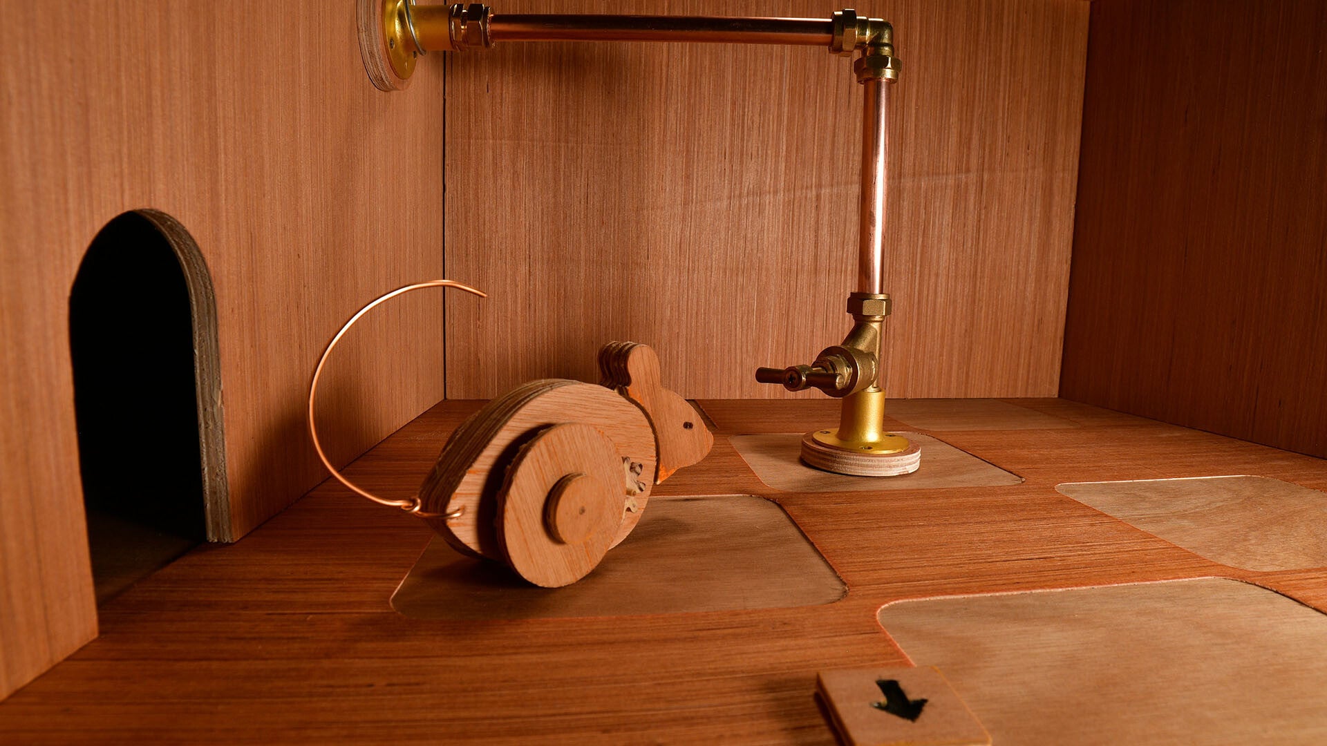 A wooden mouse on wheels investigating a valve on a brass pipe in a wooden chamber. - 5