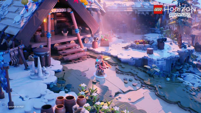 Lego Horizon Adventures screenshot showing Aloy outside a longhouse in the snow.