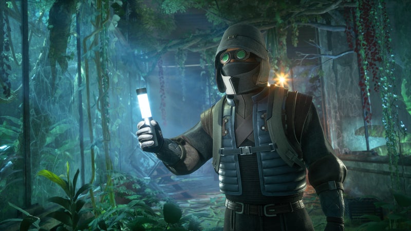 A suited, hooded and goggled figure holding a glowstick in an underground verdant area from Dune: Awakening. - 1