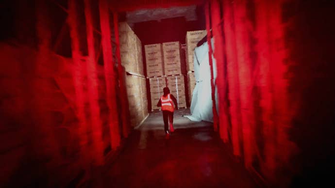 A guy in a high vis jacket running away from you down a red-lit warehouse corridor in Gangstalk