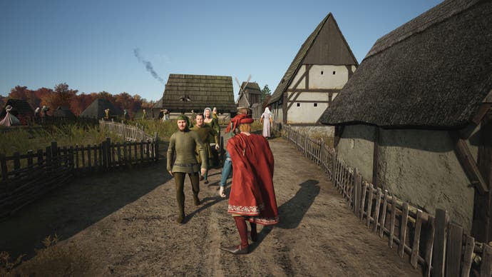 A third-person, over-the-shoulder view of Bertie's Manor Lords town. Here, he's directly controlling his richly dressed manor lord as they walk the roads Bertie built.