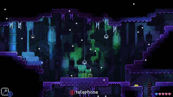 A more open area in Animal Well with a telephone at its centre and drifting flakes of matter