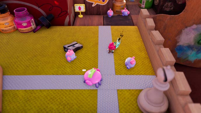 The Plucky Squire battles round cartoon bugs on top of a child’s desktop. A chess piece stands nearby as well as some bottles of paint.