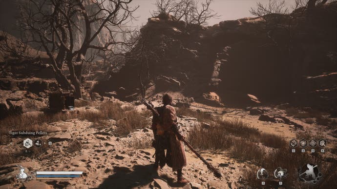 A monkey warrior stands in a sandy desert before a cave entrance in Black Myth Wukong.