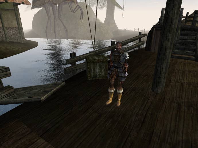 A screenshot from The Elder Scrolls 3: Morrowind showing a dark-skinned sailor standing on a boat that's docked on a small jetty in an apparent swamp of some kind.
