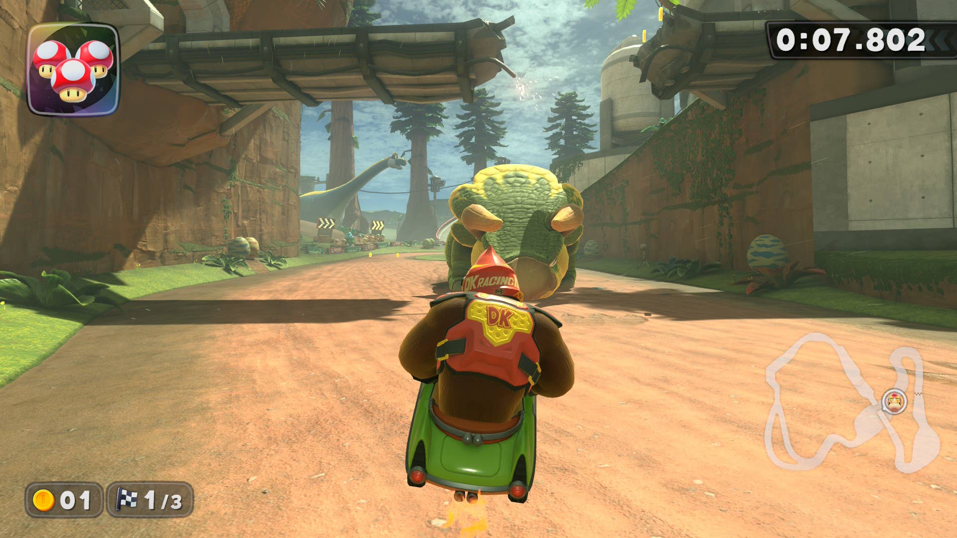 Mario Kart World screenshot showing Donkey Kong about to land in front of a dinosaur on the Dino Dino Jungle course.