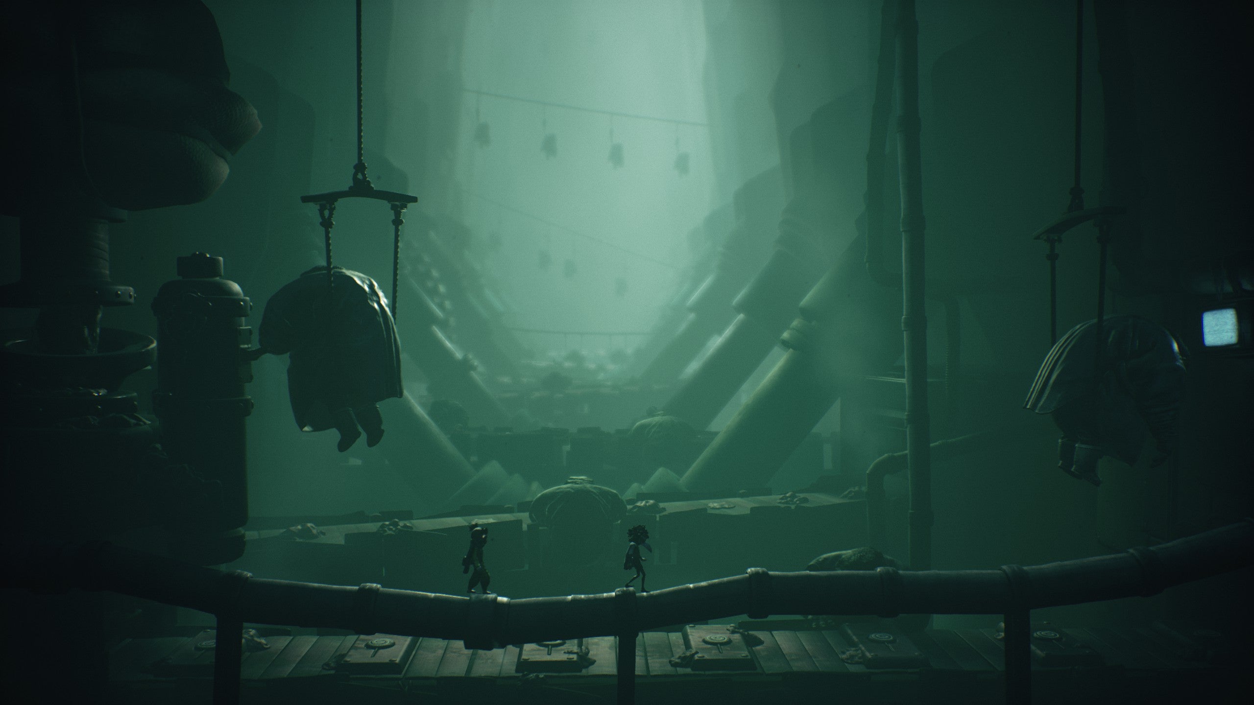 Large men are hanging from the ceiling in the factory. I think they might be sad, but maybe not.