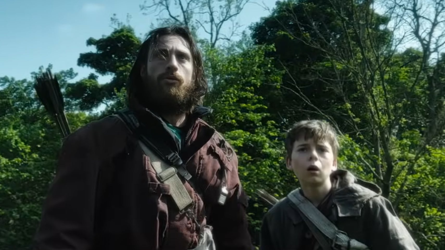 Aaron Taylor-Johnson and a teen boy looking scared stood in front of some trees in 28 Years Later. - 1