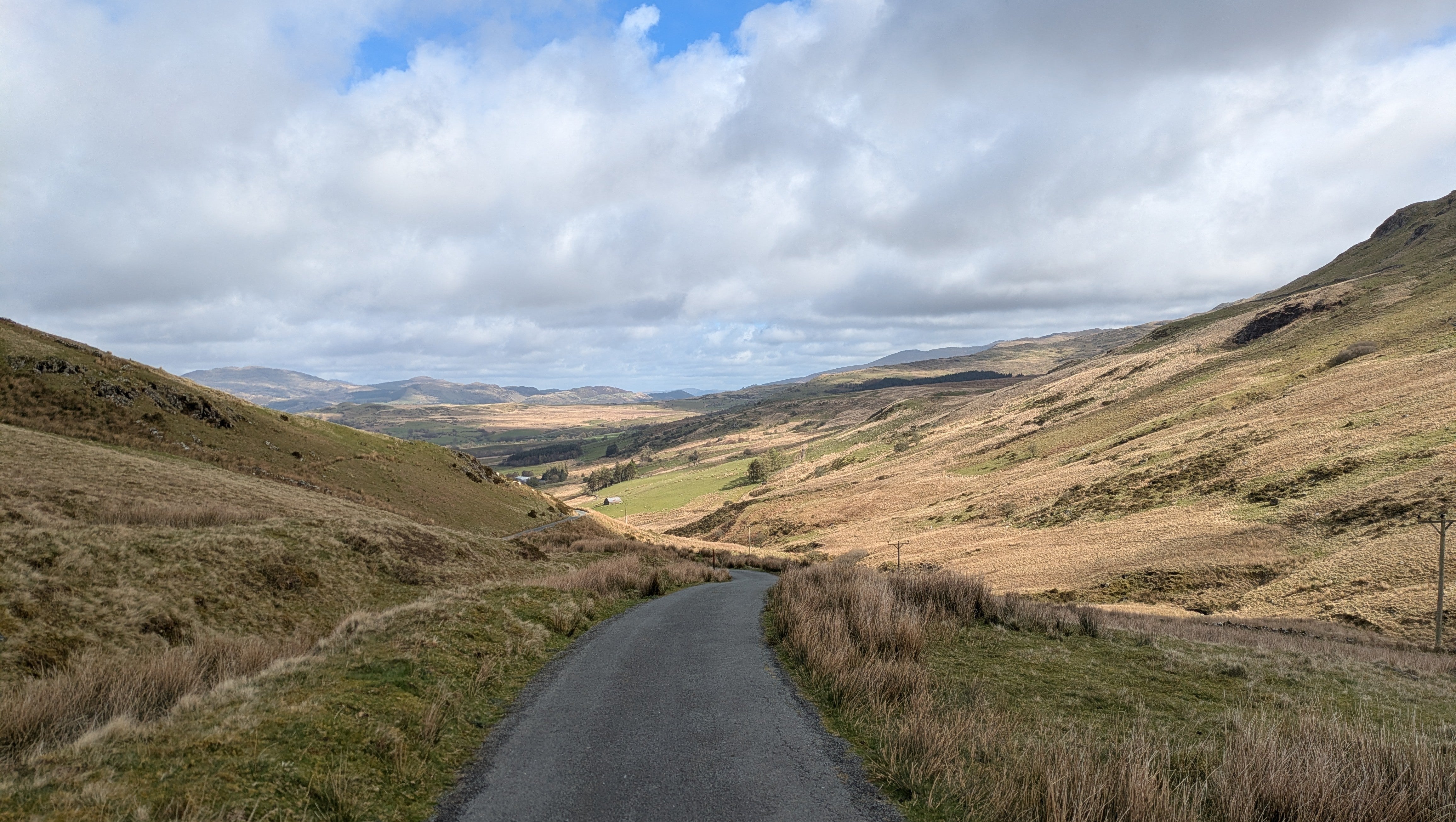 A view of a road down Welsh hillsides on a sunny day.