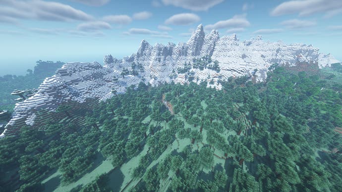 Eine massive schneebedeckte Bergkette in Minecraft, umgeben von Wald.