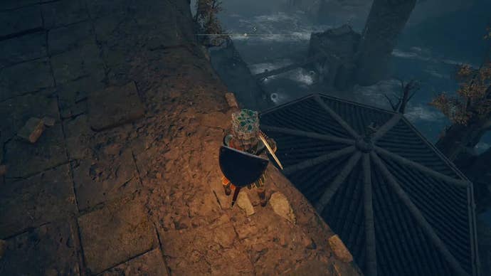 A warrior stands on the edge of a rampart overlooking a hexagonal roof in Castle Morne in Elden Ring