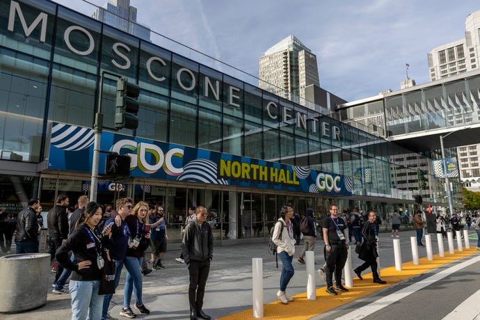 The exterior of the Moscone Center during GDC 2024 with some people standing by the side of the road