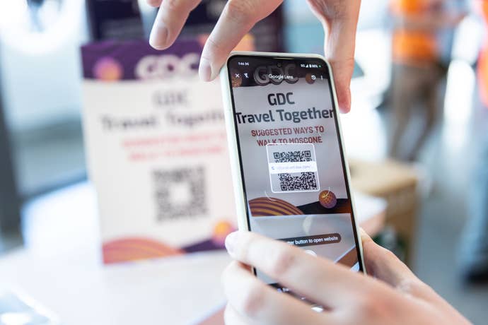 A phone taking a picture of a card that says 'GDC Travel Together'
