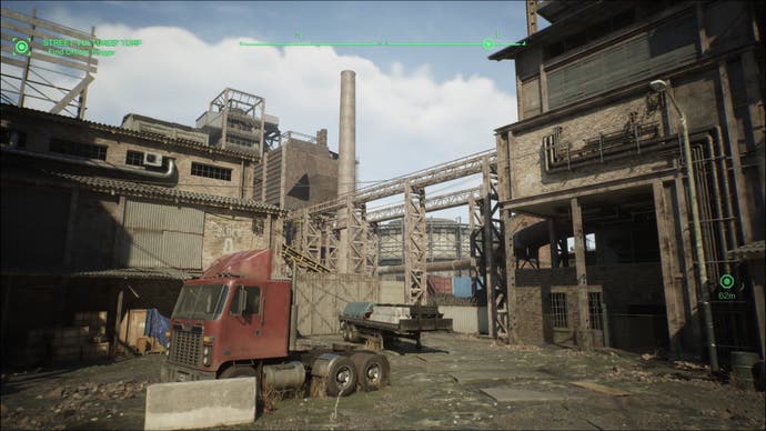 A screenshot of RoboCop: Rogue City, showing a rundown steel mill. The cab of a lorry sits in the foreground, surrounded by brick structures and an industrial chimney stack.