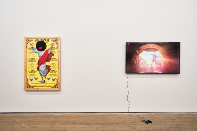 Art by Larry Achiampong showing a white Jesus, but with his face covered by a dark circle with bright red lips. Next to it on a gallery wall is a TV screen running the game BioShock Infinite