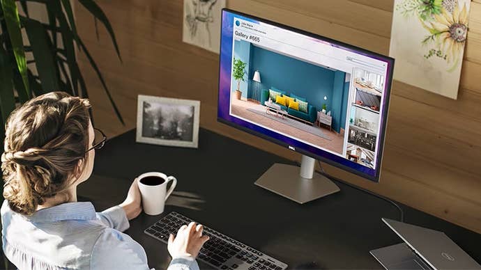 a dell s2721ds office monitor sits on a desk while a woman with nice hair holds a coffee cup and gazes ahead, one hand on her keyboard.