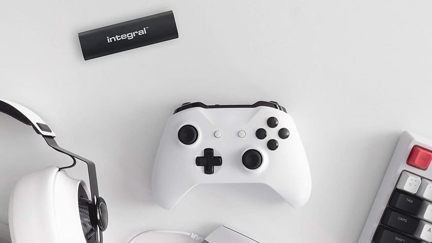 a photo of an integral usb-c portable ssd, alongside a game controller, set of headphones and computer keyboard