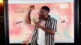A man holds up several red gummy sweets which he has pulled from a paper bag while playing a game from the Jackbox Naughty Pack