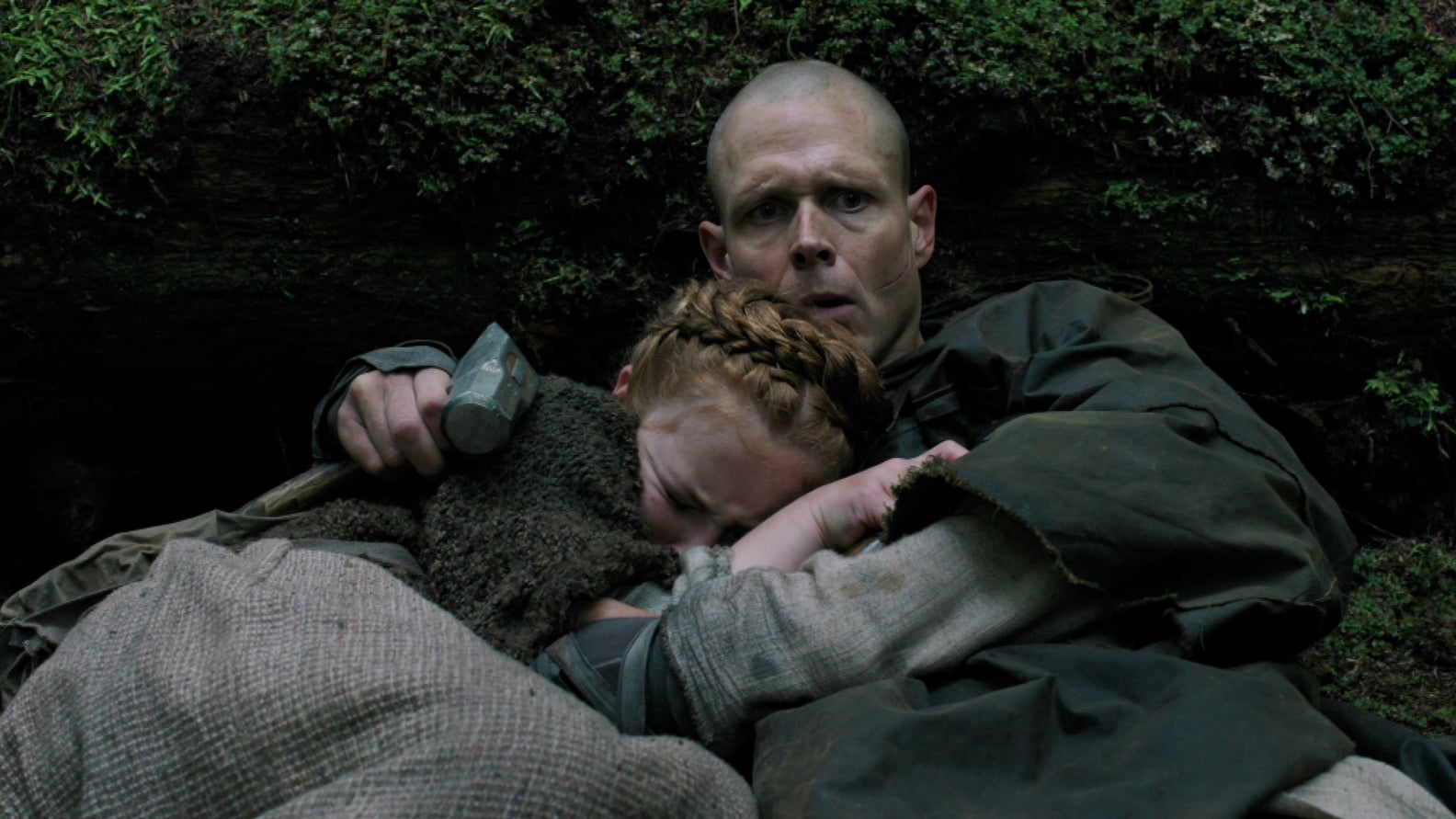 A young Seraphite girl cuddles into a man as they hide in The Last of Us season two