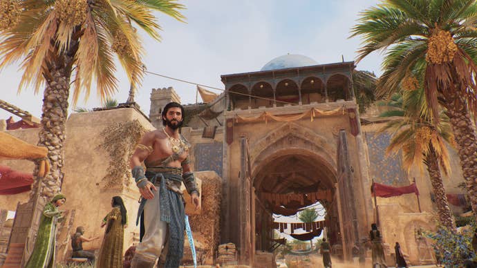 Basim stands in front of a gate amidst palm trees and other civilians in Assassin’s Creed Mirage