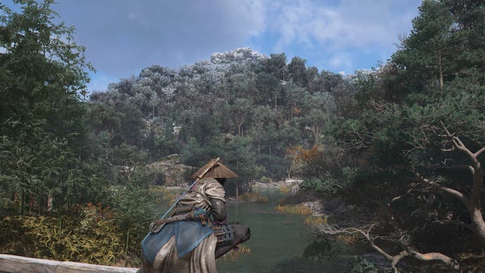 AC Shadows screenshot showing Naoe perched on a fence overlooking a lake and forest