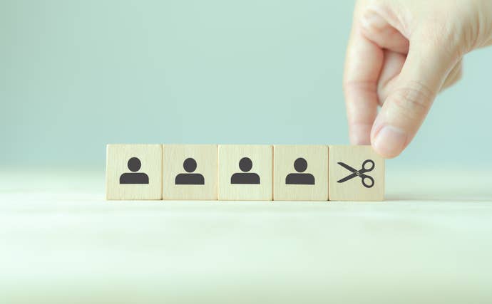 Artwork showing tiles representing people and another with a pair of scissors, illustrating cuts to personnel.