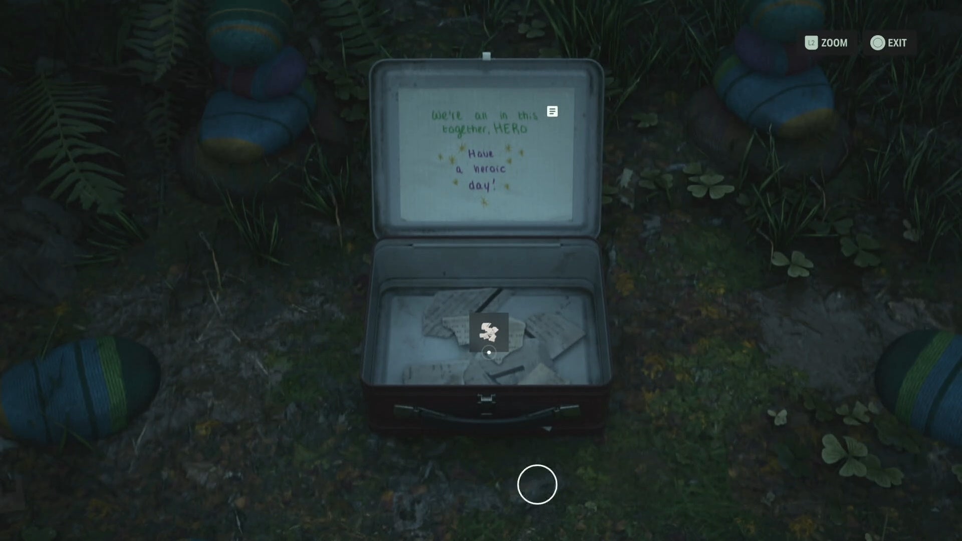 first person view of an open lunch box on a forest floor, with colourful knitting balls placed around it in a circle and a note reading &ldquo;We&rsquo;re all in this together hero. Have a heroic day&rdquo; inside the lunch box