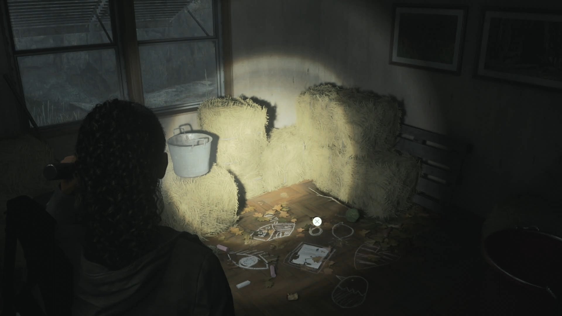saga shining her flashlight on a nursery rhyme puzzle in a small room in a trailer containing stacks of hay