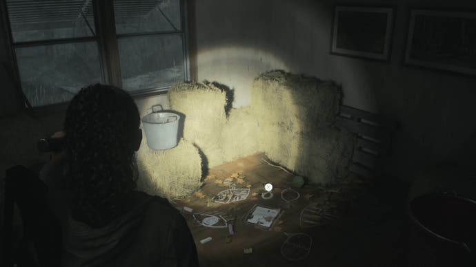saga shining her flashlight on a nursery rhyme puzzle in a small room in a trailer containing stacks of hay