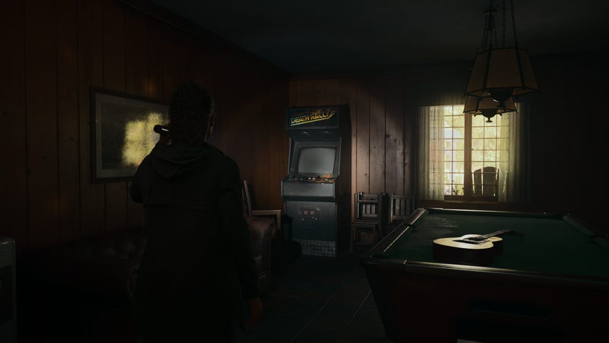 A screenshot from Alan Wake 2 showing a “Death Rally” arcade machine in a very dark room.