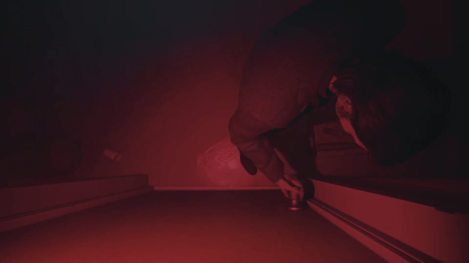 top-down perspective of alan trying to open a door, with a deep red filter applied