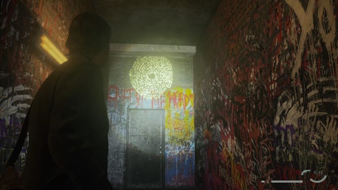 alan shining his flashlight on a word of power above a door in a narrow outdoor corridor with the walls covered in colourful graffiti