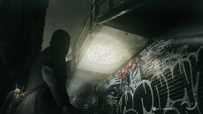 alan shining his flashlight on a word of power printed under a set of outdoors stairs with graffiti on the wall below the stairs