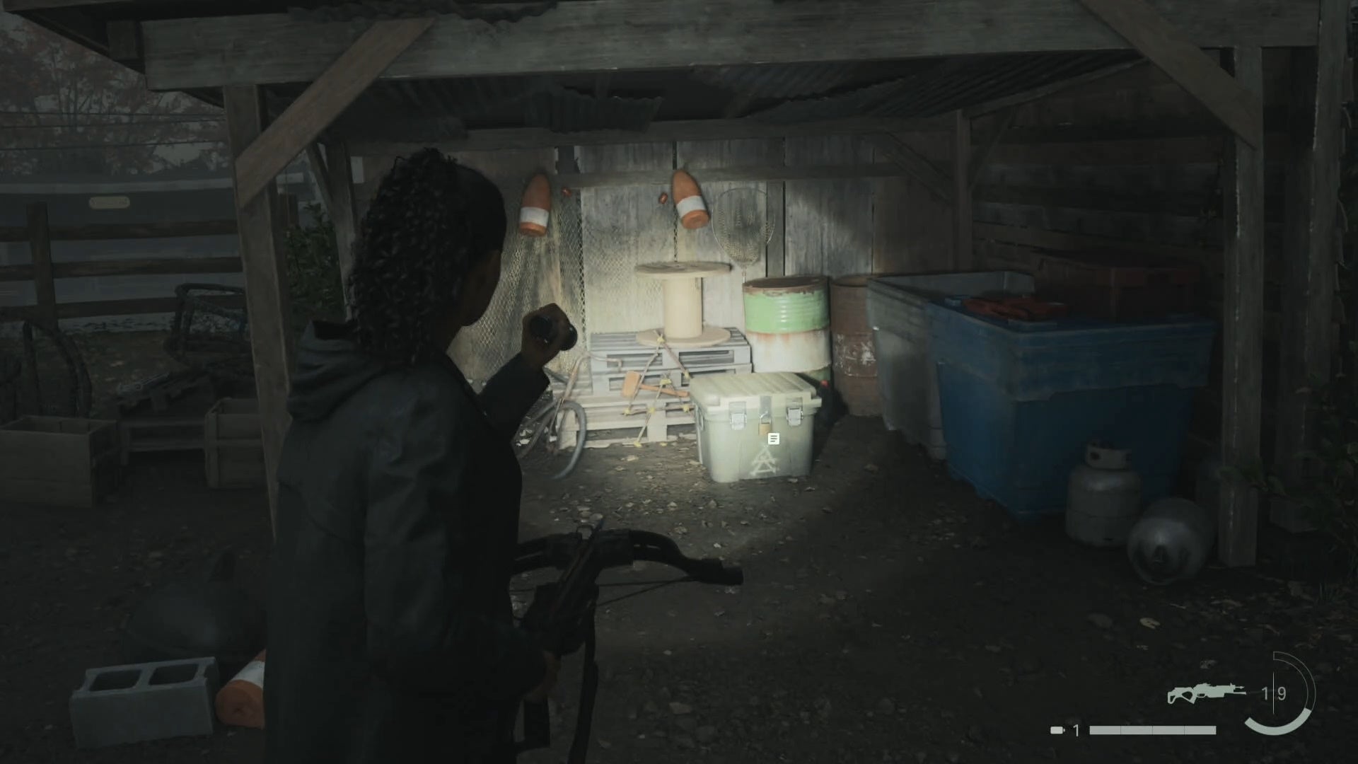 saga shining her flashlight on a cult stash in a wooden structure in a trailer park