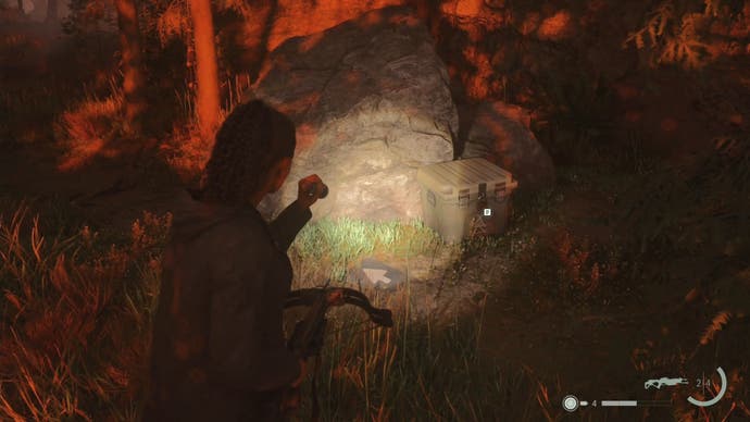 saga shining her flashlight on a cult stash by a large rock in the woods