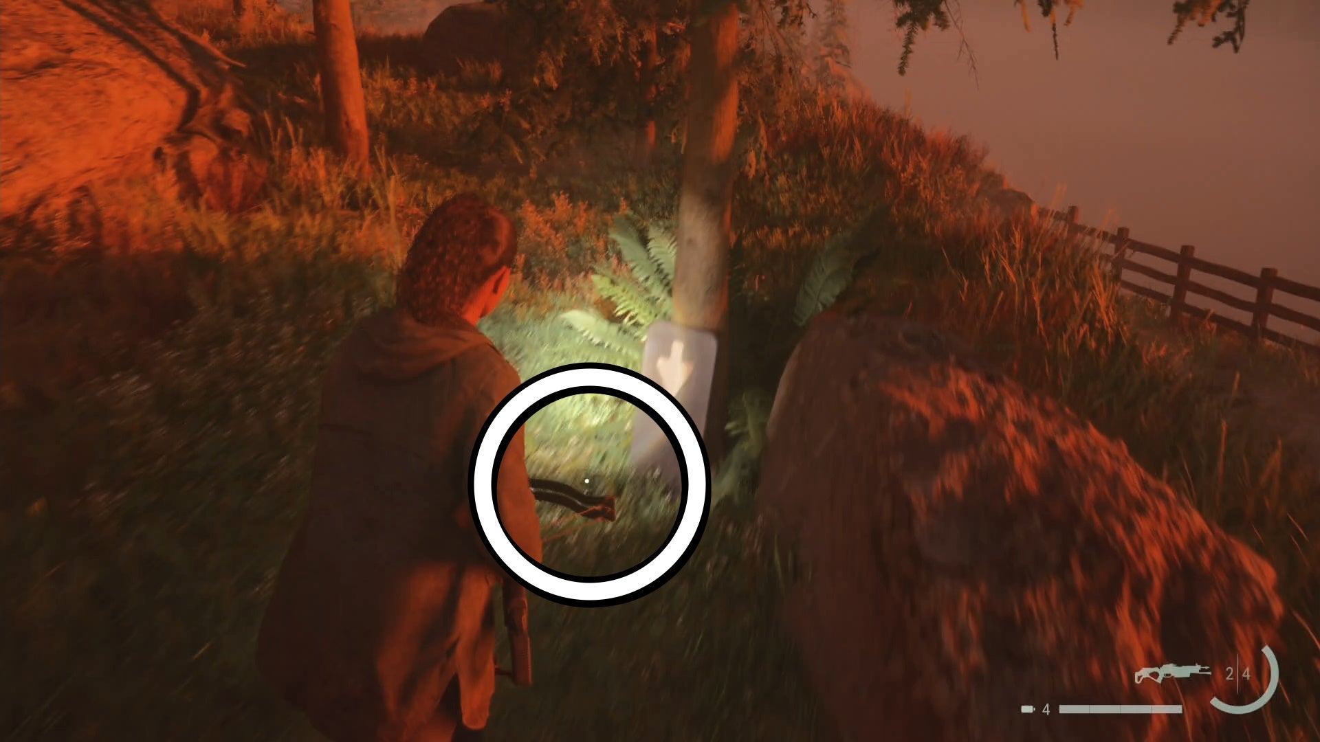 saga shining her flashlight on a cult stash key below an arrow printed on a sign, under a tree in the woods