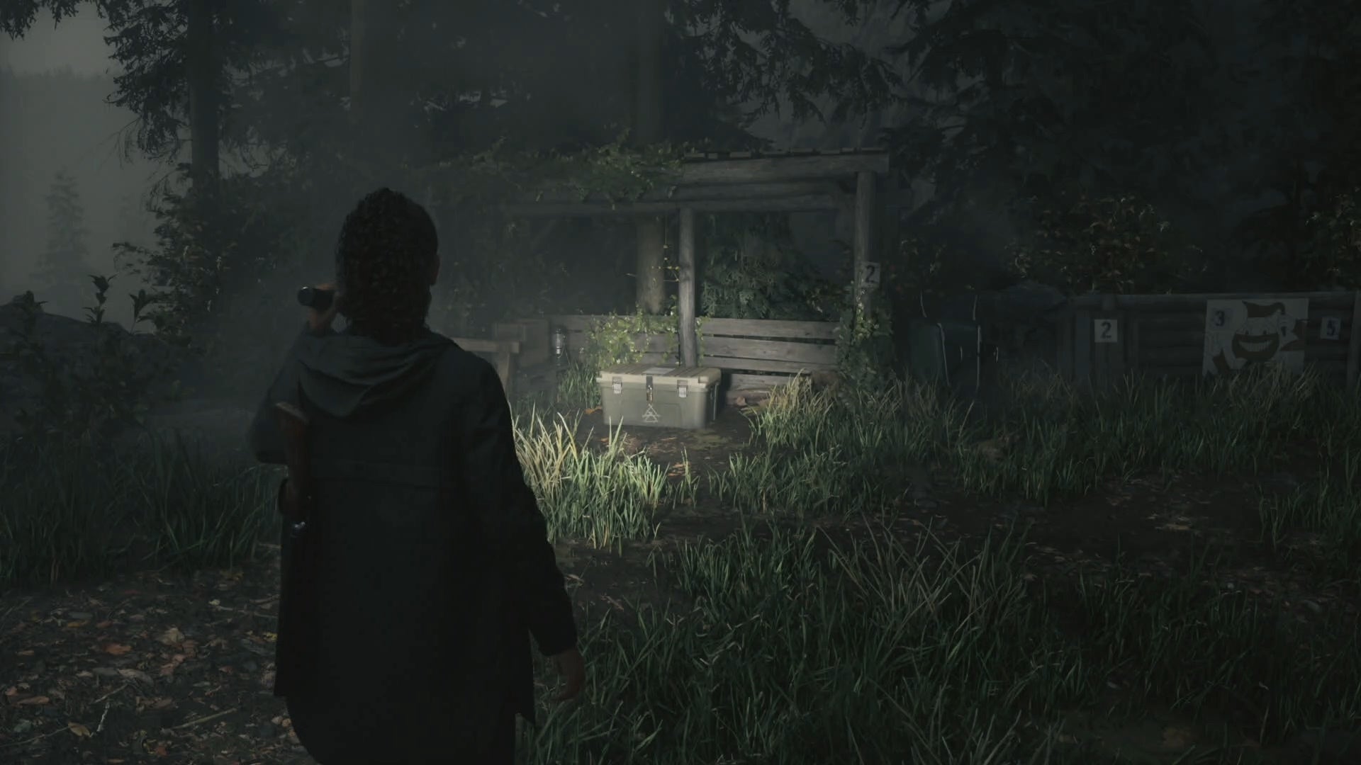 saga shining her flashlight on a cult stash on grass by a small wooden wall