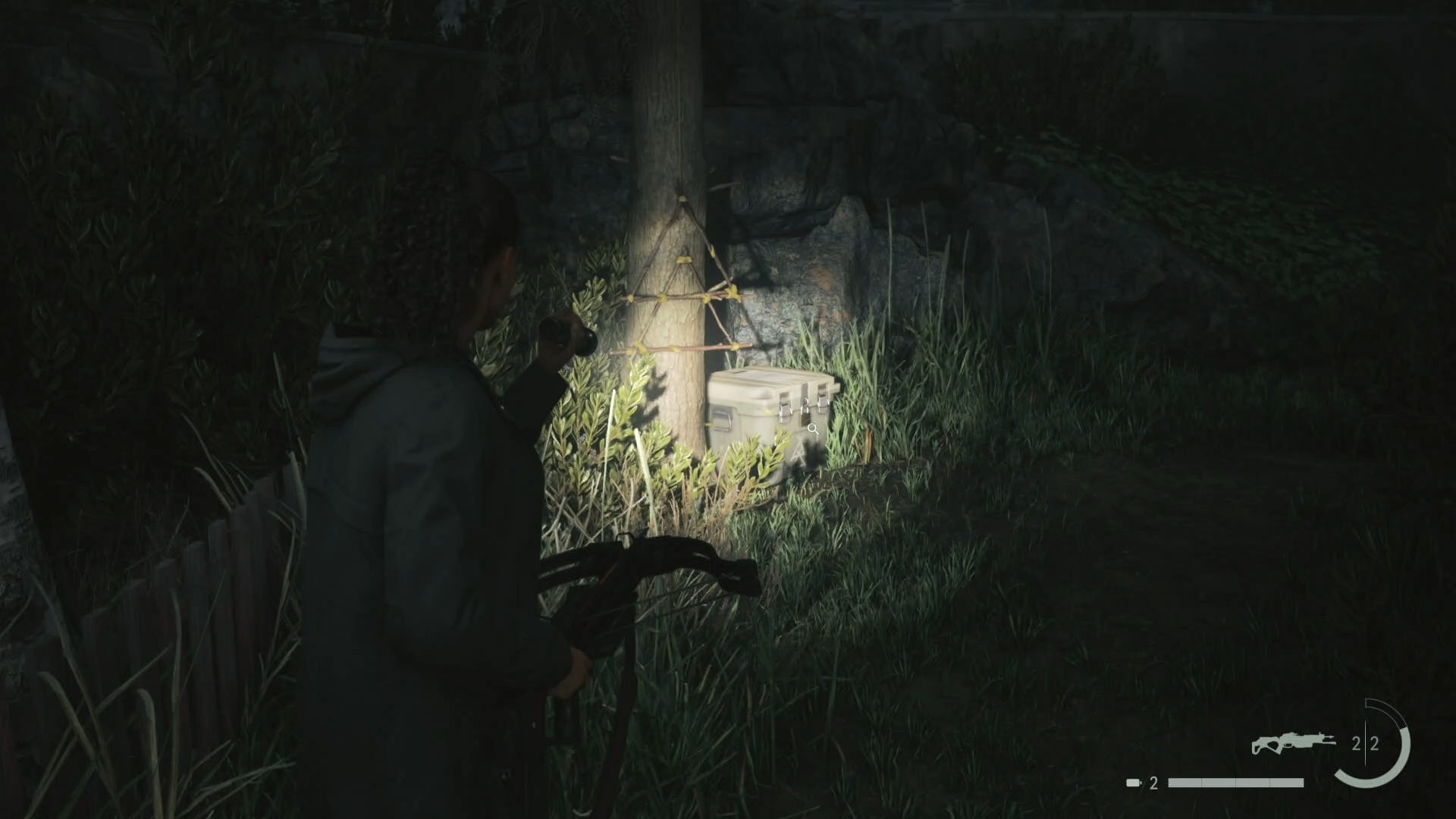 saga shining her flashlight on a cult stash near a tree in the woods