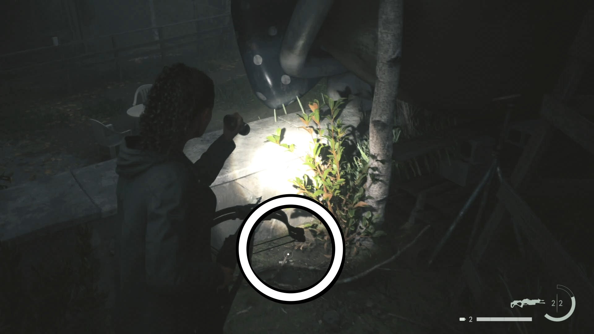 saga shining her flashlight on a key on the forest floor beside a thin tree