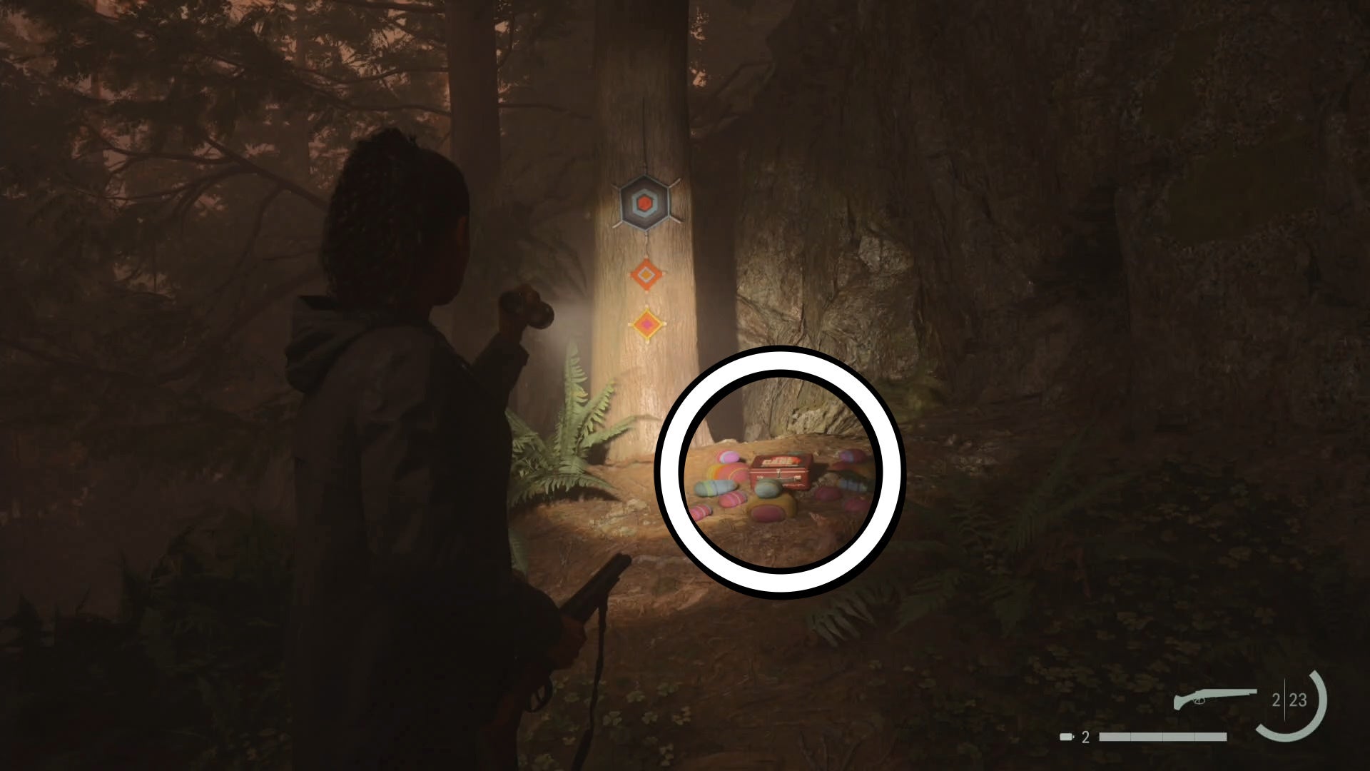 saga shining her flashlight on a lunch box below a tree in the forest with colourful knitting hanging from the tree